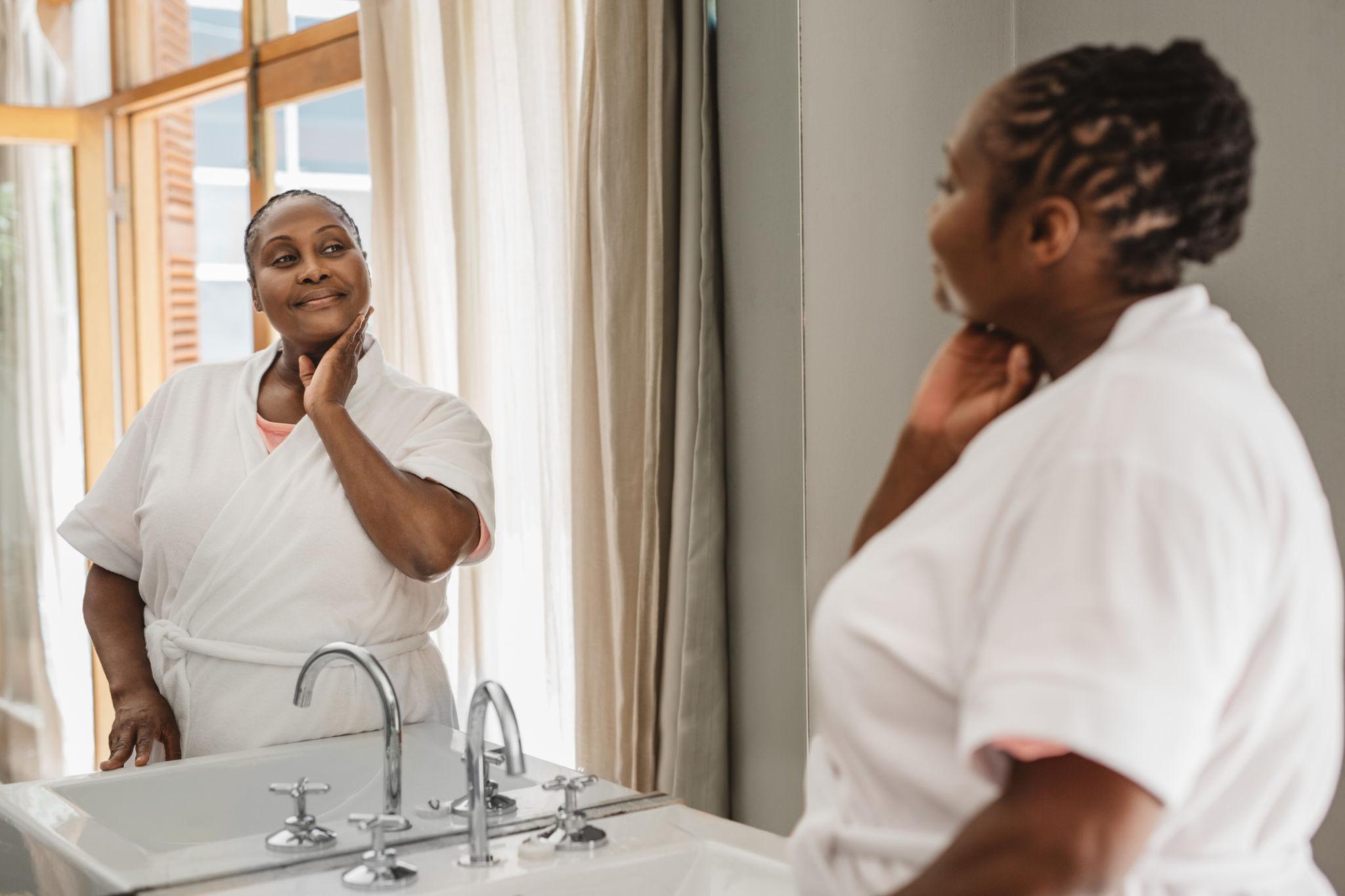Woman in a bathrobe looking in the mirror